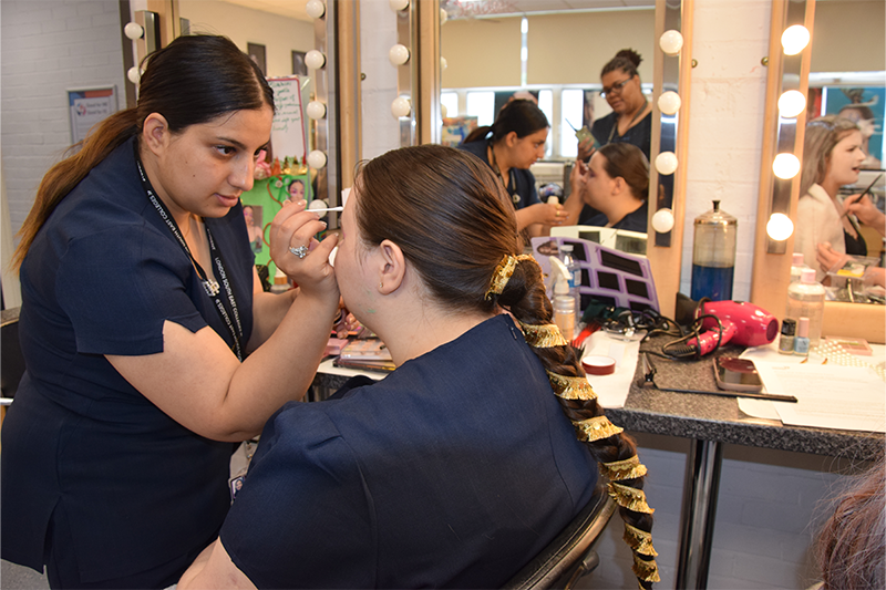 Student putting make up on model